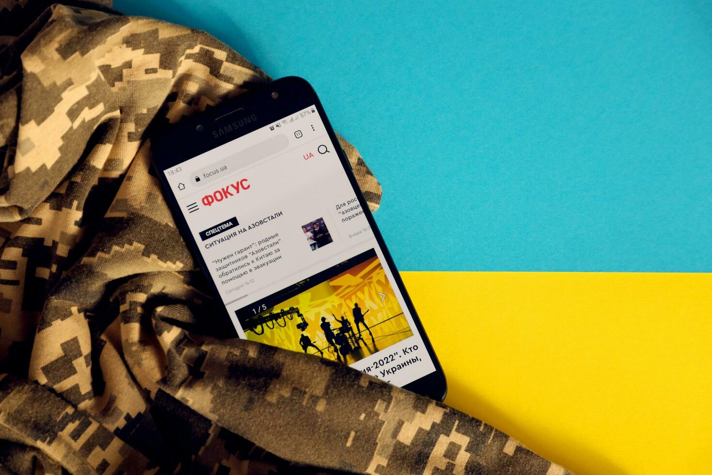 KYIV, UKRAINE - 4 MAY, 2023 Focus ukrainian news portal on smartphone screen with ukrainian flag and camouflage fabric photo