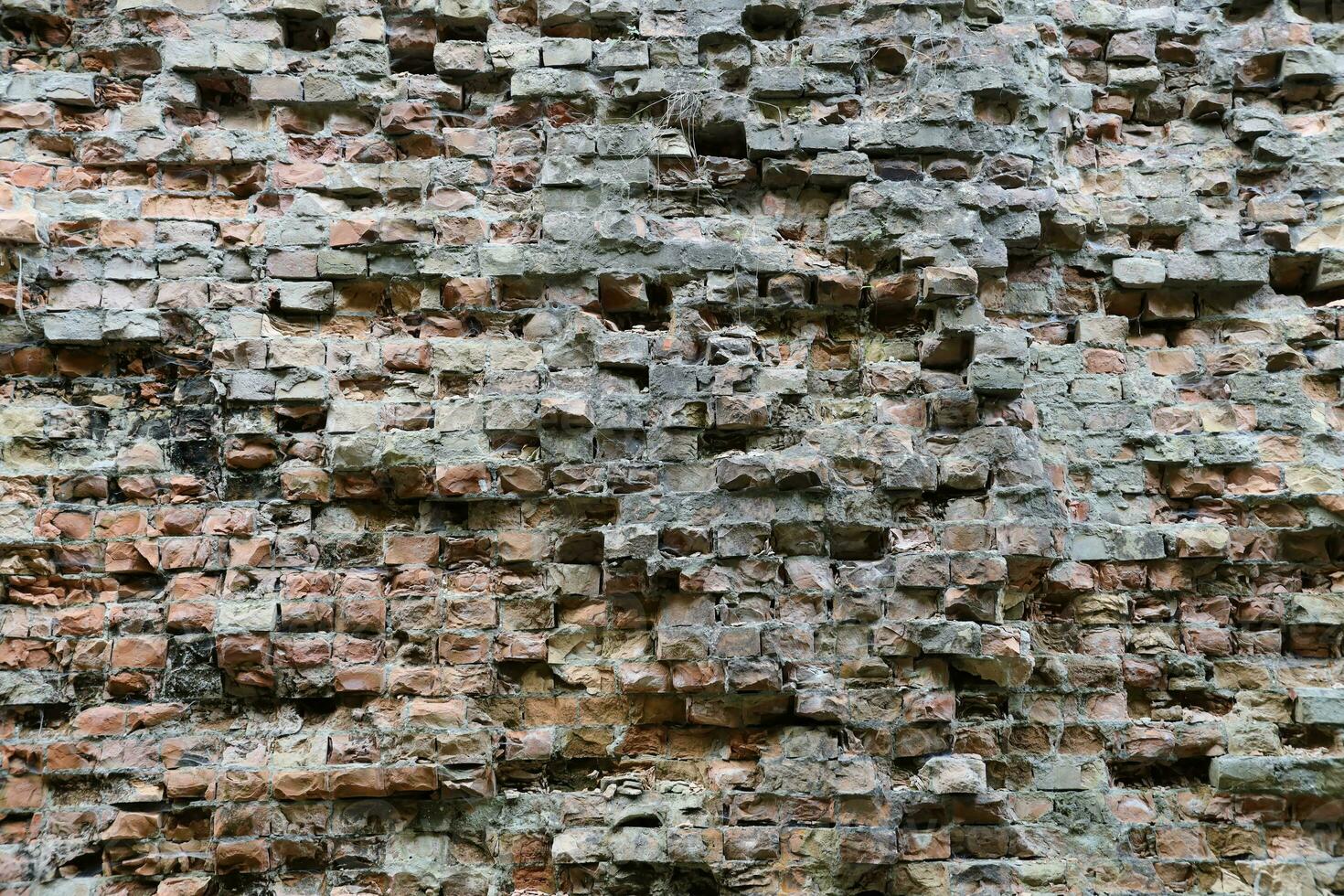 Very old brick stone wall of castle or fortress of 18th century. Full frame wall with obsolete dirty and cracked bricks photo
