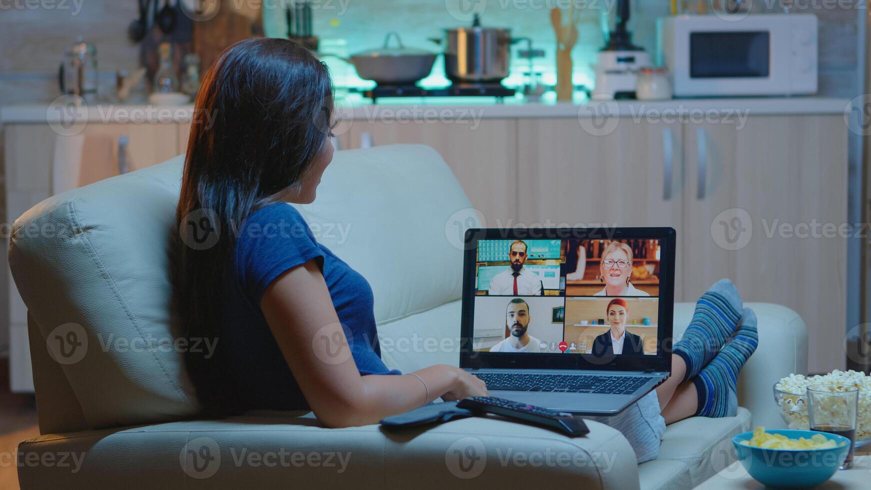 Woman freelancer having web chat conference sitting on sofa in living room. Remote worker discussing at online meeting, consulting with colleagues using videocall and webcam working in front of laptop photo