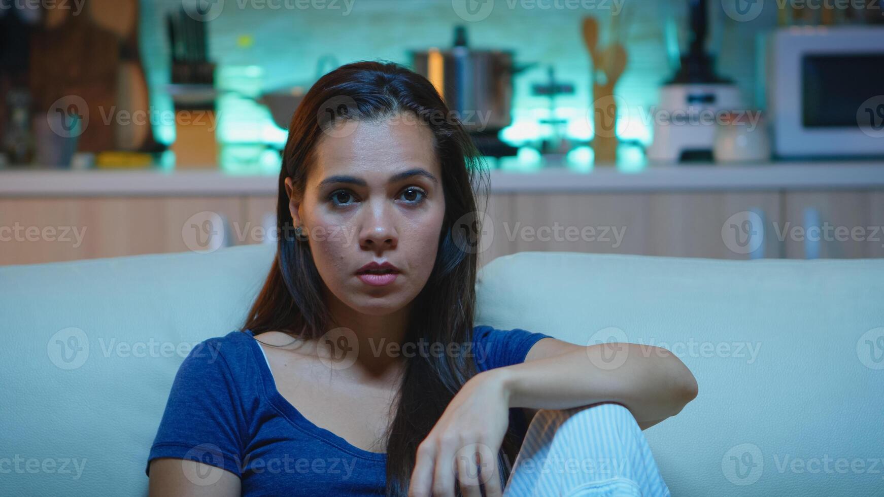 Woman watching television show very concentrated and amazed. Lady with surprised face emotionally awestruck and wide-eyed reacting to an impressive and astonishing moment sitting on comfortable couch photo
