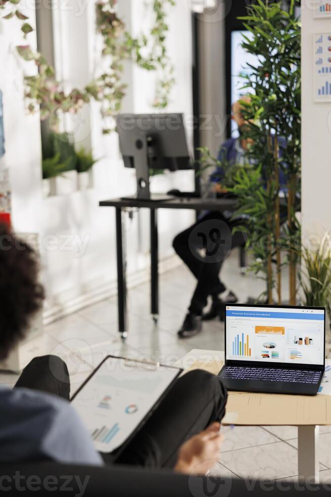 Entrepreneur comparing sales metrics and analyzing market data on laptop in business office. Financial analyst doing performance analysis and roi calculation in start up company photo