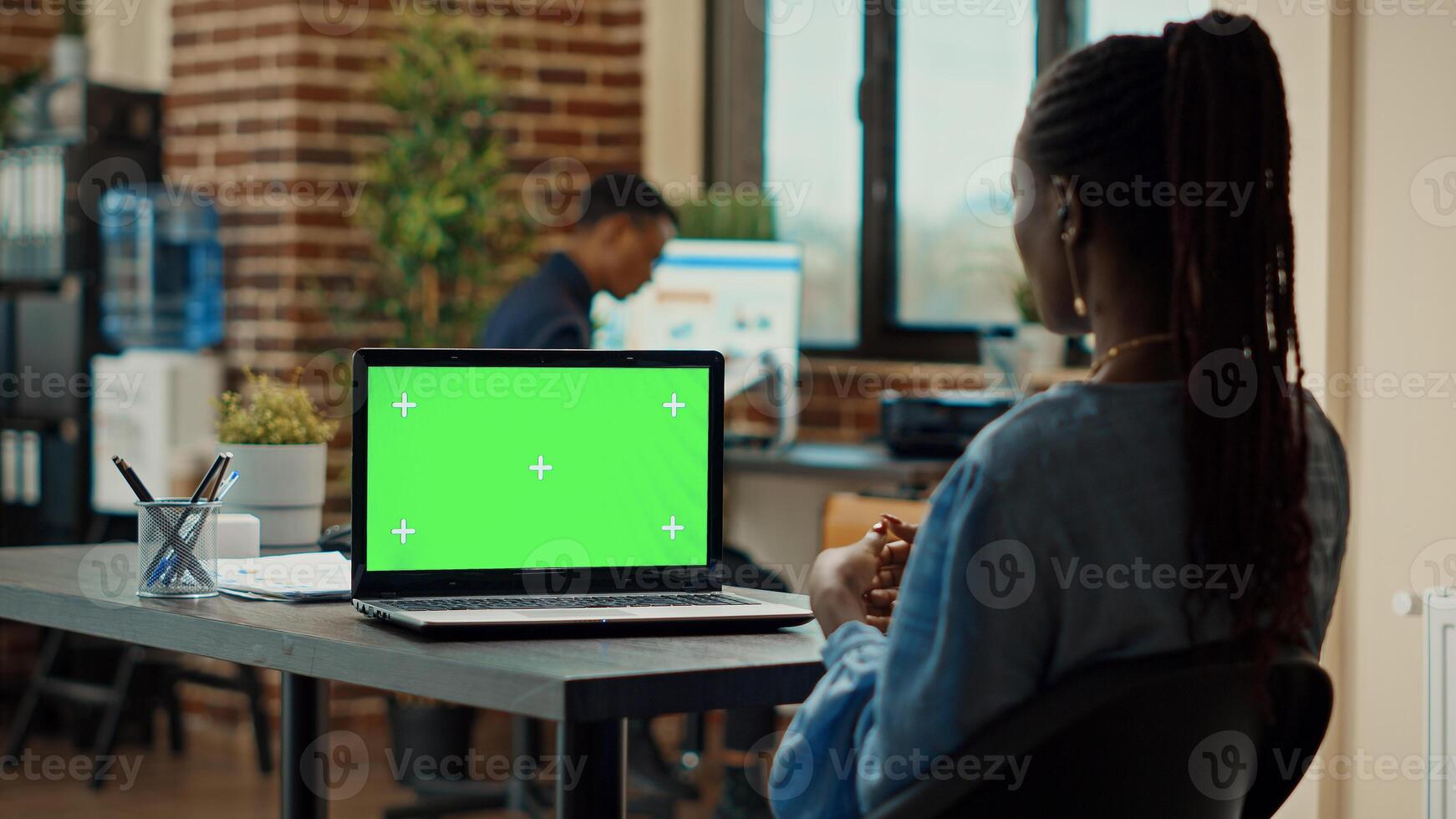 Manager working with greenscreen in business office, looking at blank chroma key display. Company employee using isolated mockup template and copyspace on laptop, coworking space. Tripod shot. photo