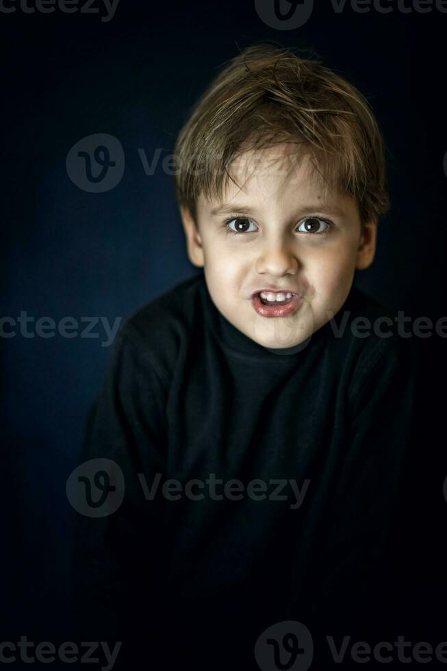 A concise portrait of a European boy. Portrait on a dark background. photo