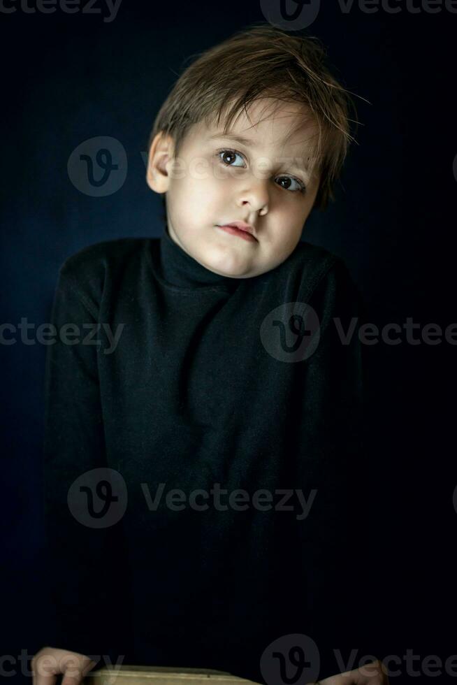 A concise portrait of a European boy. Portrait on a dark background. photo