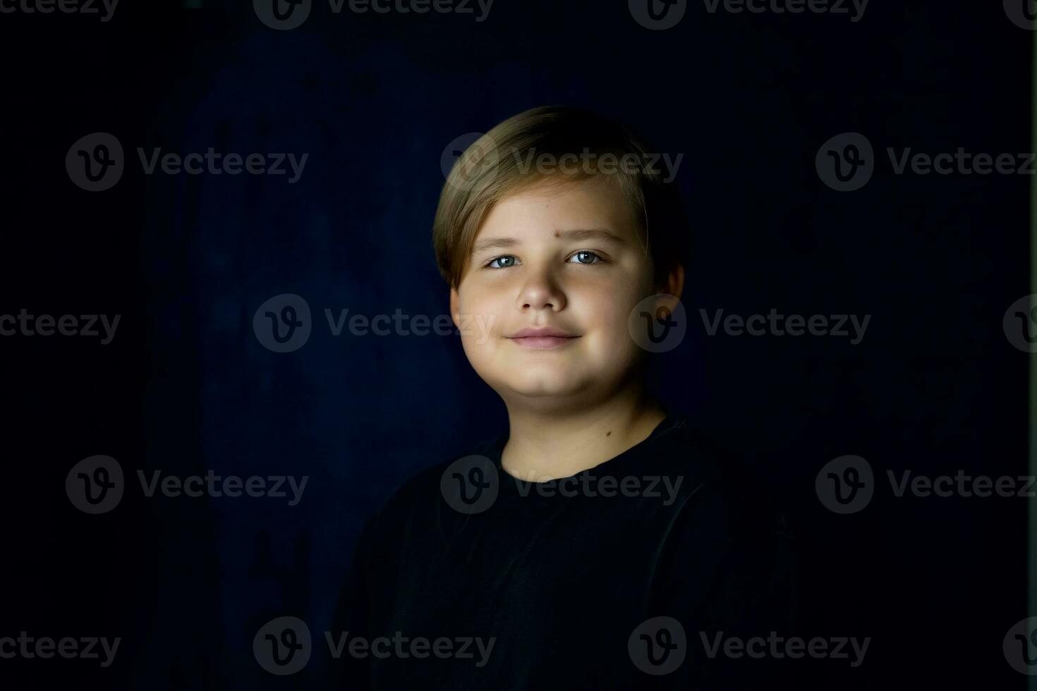 A concise portrait of a European boy. Portrait on a dark background. photo