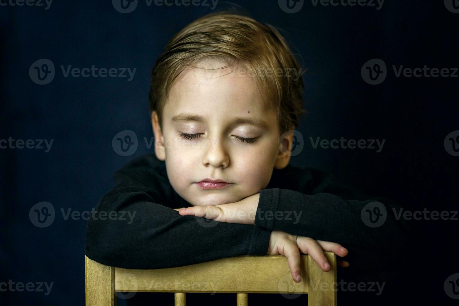 A concise portrait of a European boy. Portrait on a dark background. photo