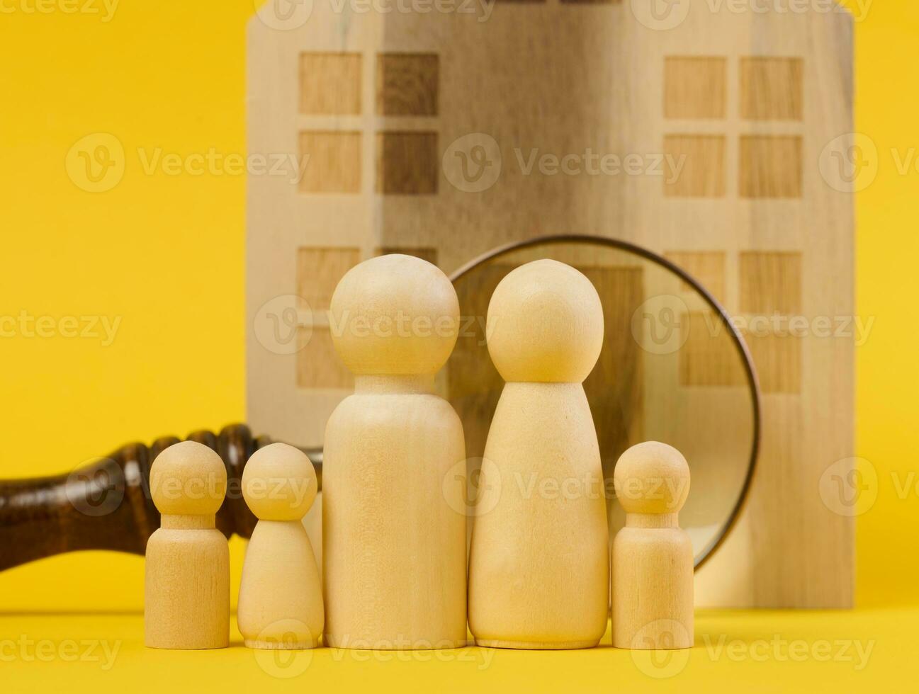 Magnifying glass and a family of wooden figures on the background of a house, the concept of searching for real estate rental, mortgage photo