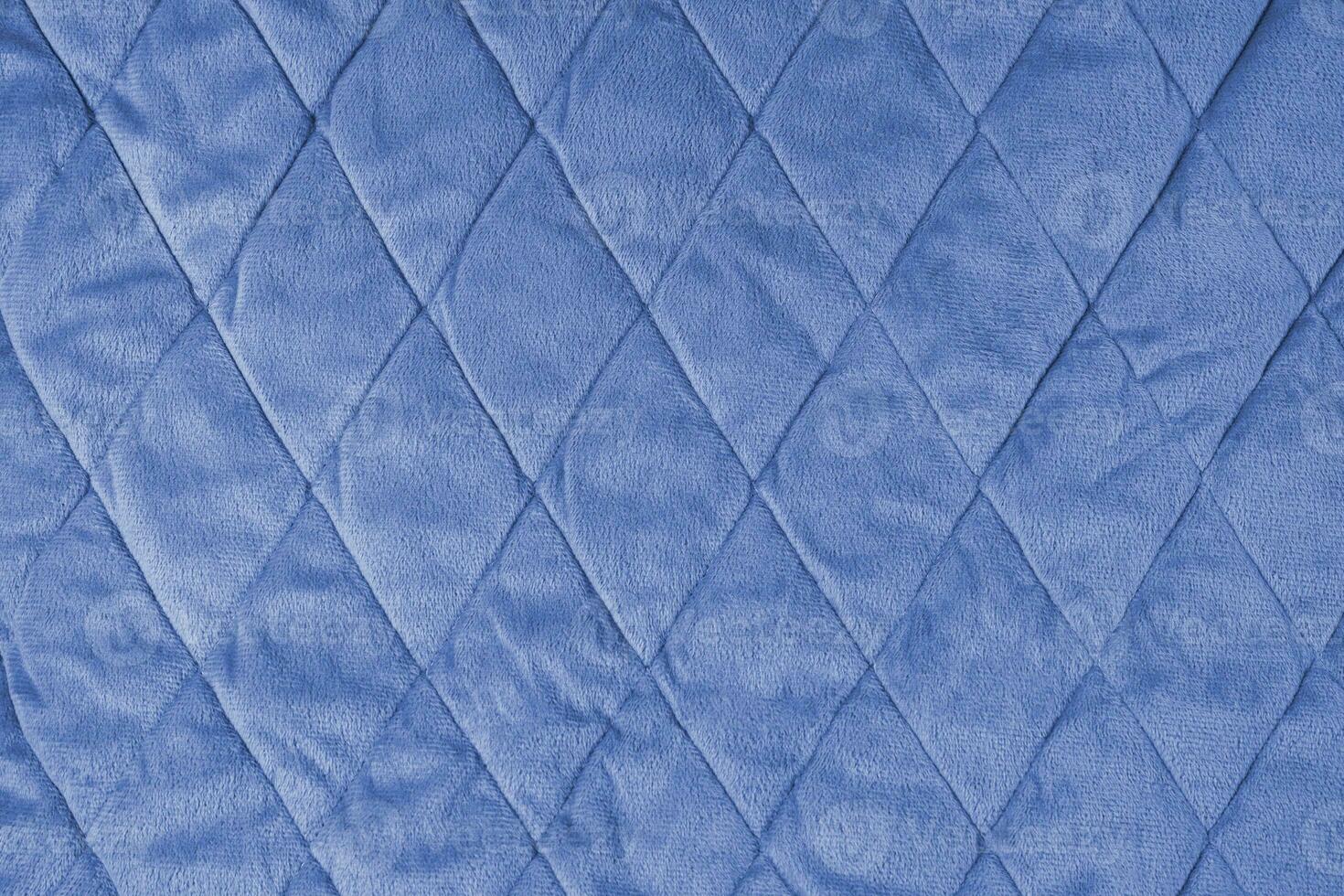 Quilted blue velours fabric background, wrinkled soft blanket surface photo