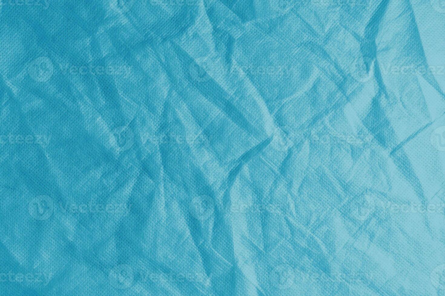 Wrinkled, crumpled blue spunbond fabric texture background photo