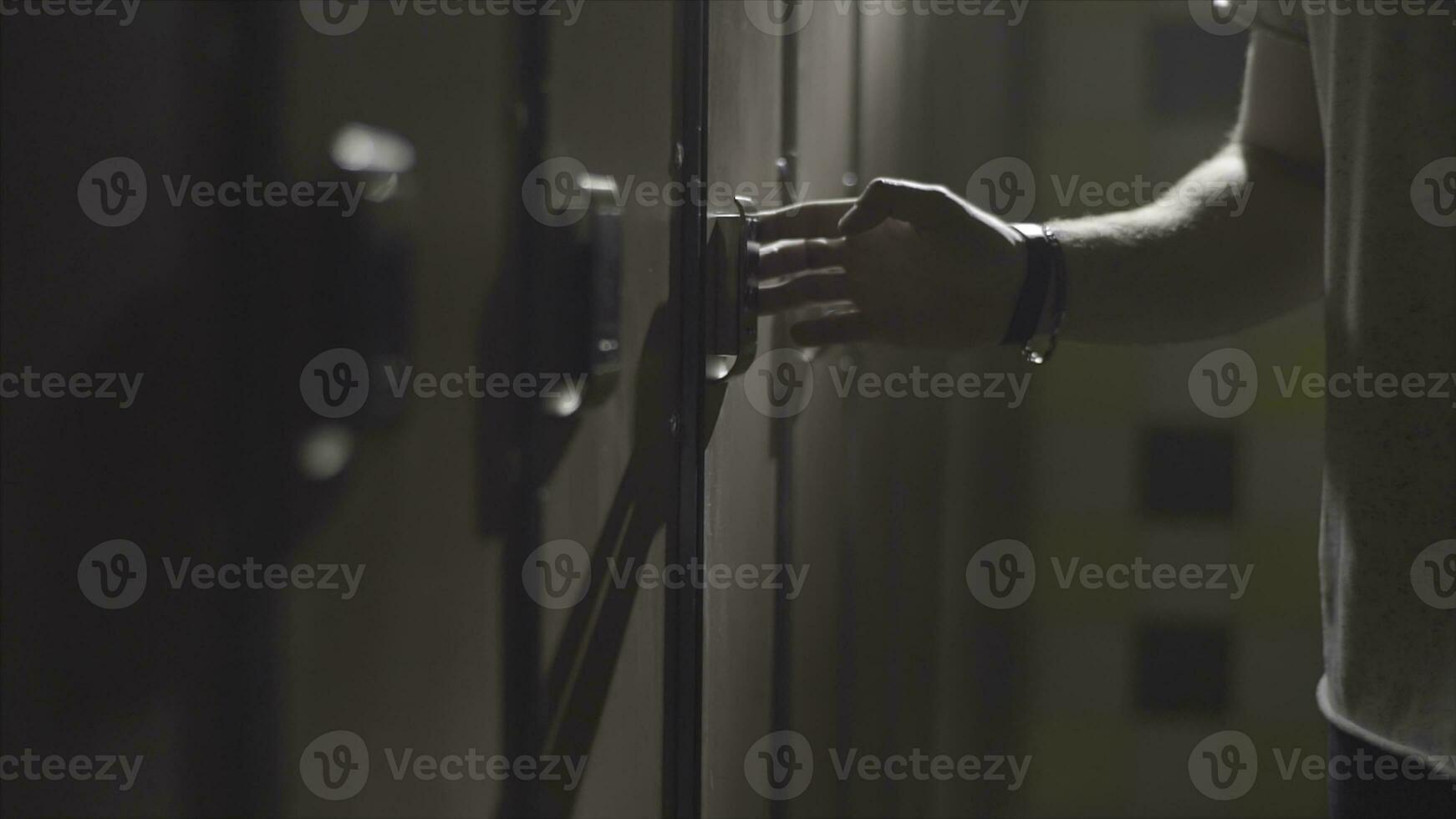 Man's hand opening locker with electric key on his wrist at gym in the changing room. Frame. Close up hand opening the locker door in the changing room of a gym. photo