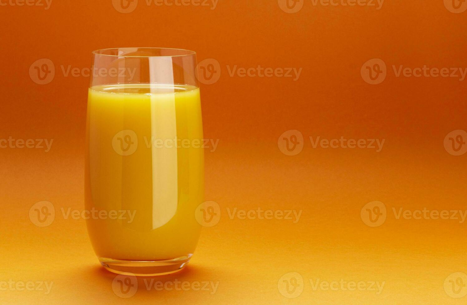 Glass of orange juice isolated on orange background with copy space photo