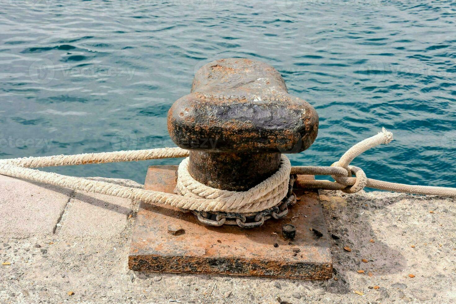 a rusted anchor on a dock with rope photo