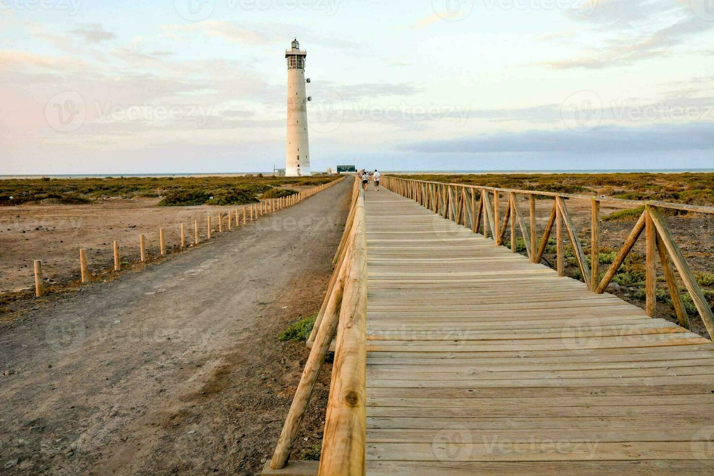 a wooden walkway leads to a lighthouse in the middle of the desert photo