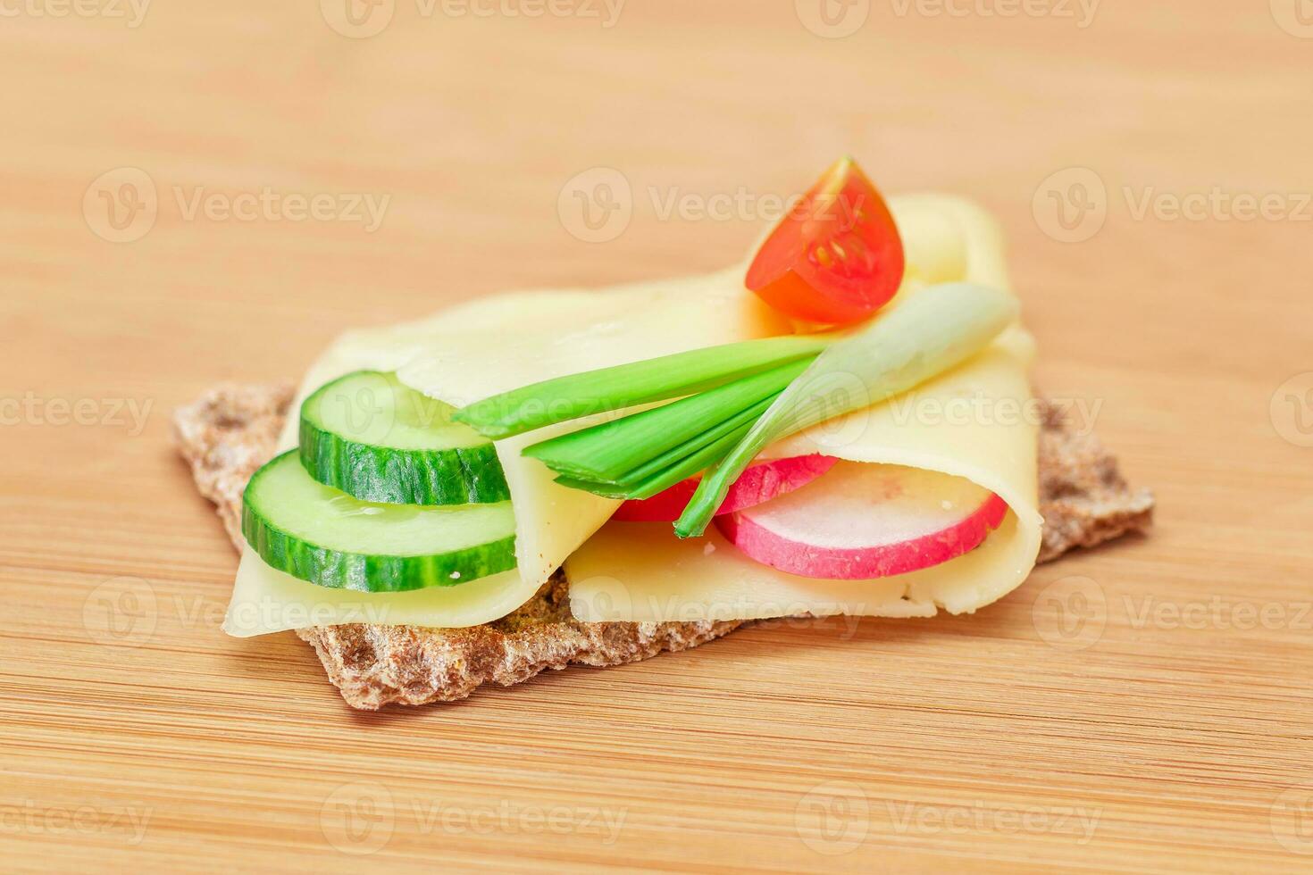 Whole Grain Crispbread with Cheese, Fresh Cucumber, Radish, Tomato and Green Onions on Cutting Board. Quick and Healthy Sandwiches. Crispbread with Tasty Filling. Healthy Dietary Snack photo