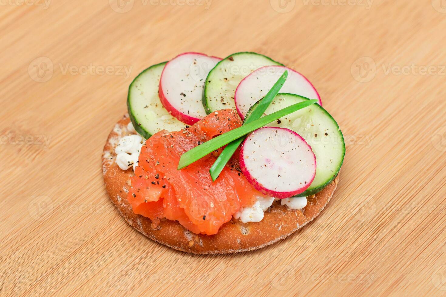 Crispy Cracker Sandwich with Salmon, Cucumber, Radish, Cottage Cheese and Green Onions on Bamboo Cutting Board. Easy Breakfast. Quick and Healthy Sandwiches. Crispbread with Tasty Filling photo