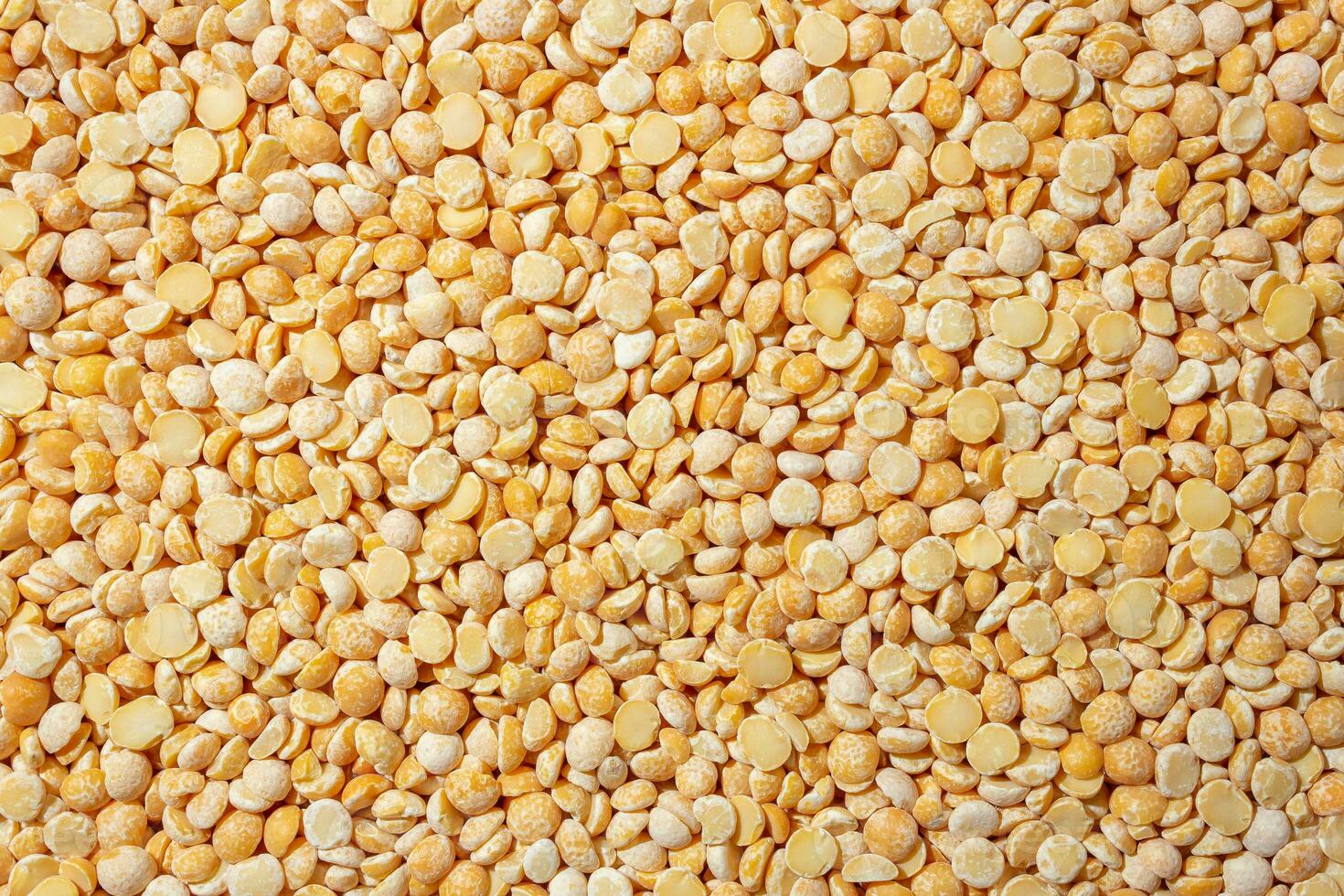 Uncooked Polished Split Peas Background. A Culinary Canvas of Dry Yellow Peas, Creating a Lively and Textured Background for Gourmet Cooking. Scattered Raw Polished Peas. Healthy Eating Ingredients photo