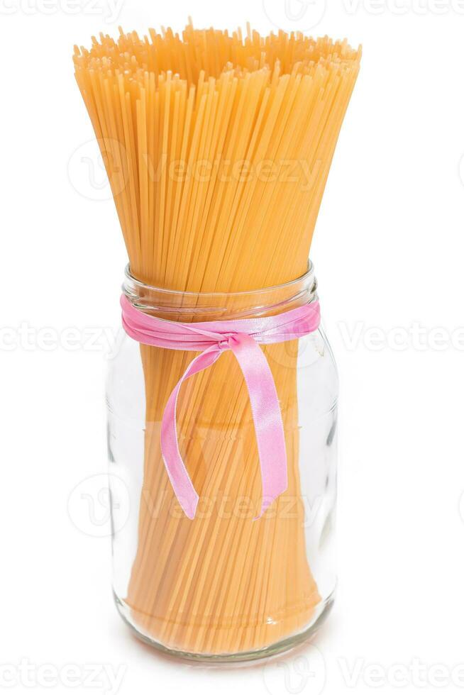 seco sin cocer espaguetis en un vaso tarro aislado en blanco antecedentes. crudo pasta - aislamiento foto