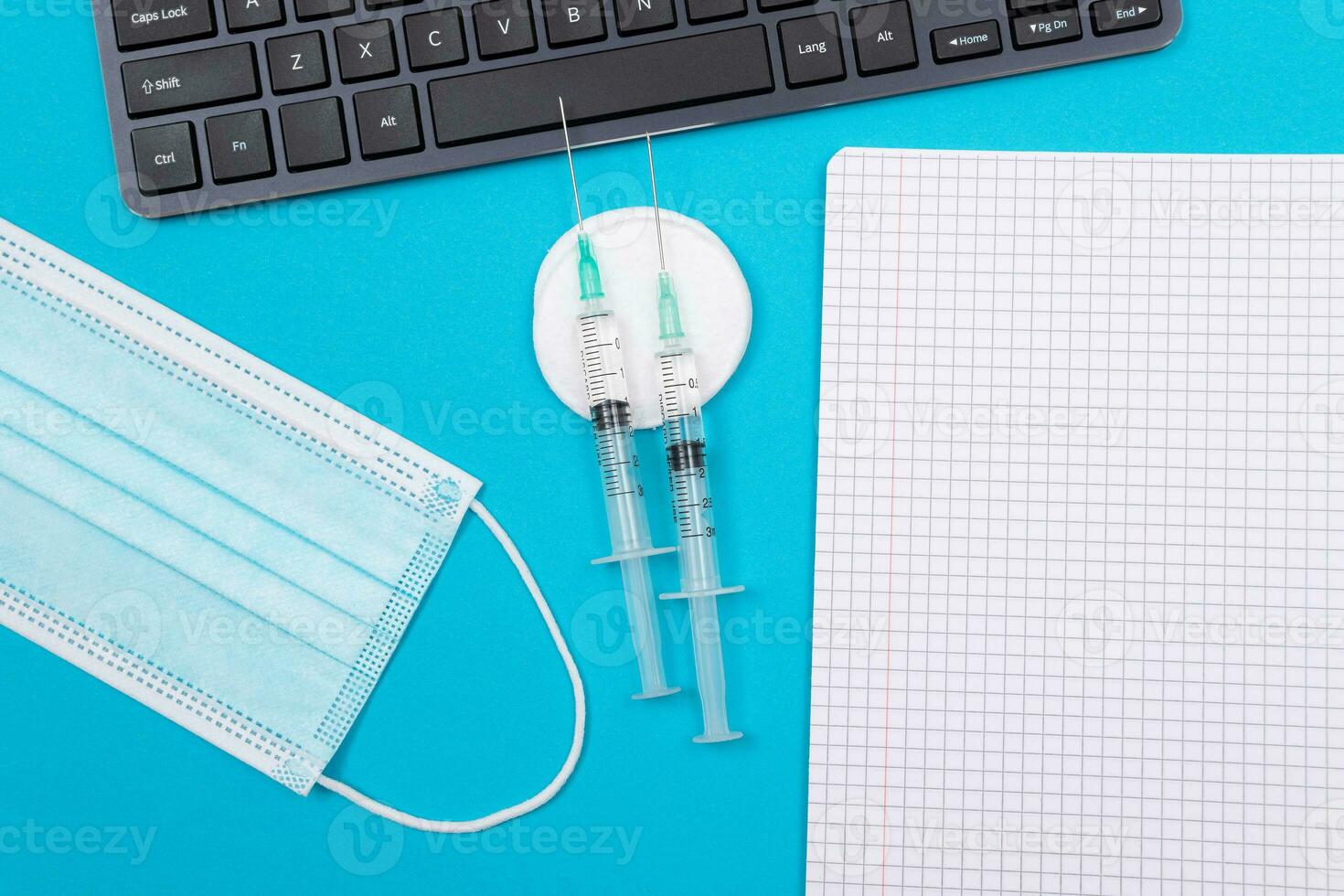 Vaccination, Immunology or Revaccination Concept Two Medical Syringe Lying on Blue Table in Doctor's Office in a Hospital or Clinic. Opened Blank Notepad Mock Up with Copy Space photo
