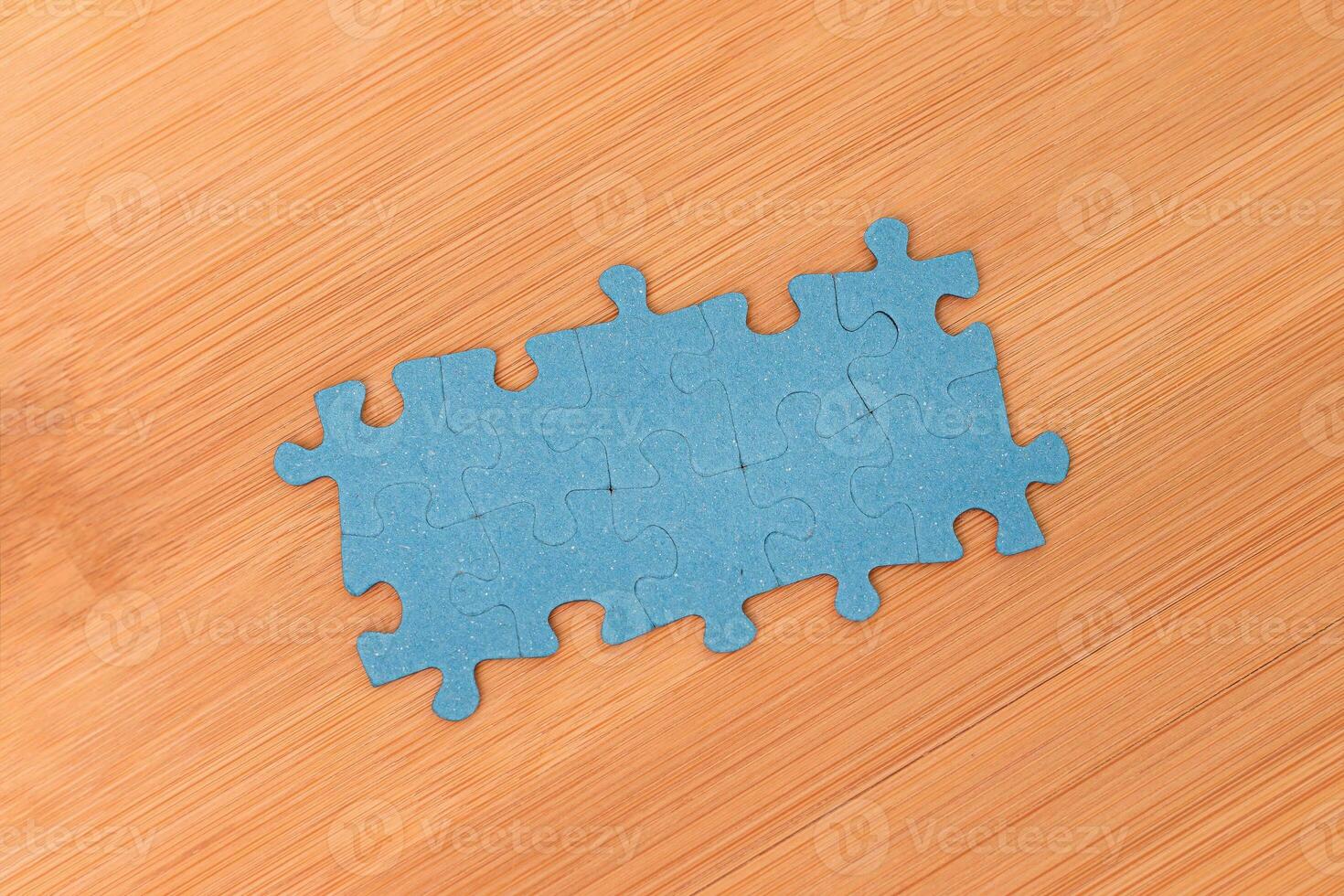 Top View of a Blue Puzzle Peaces Lie on the Wooden Table photo