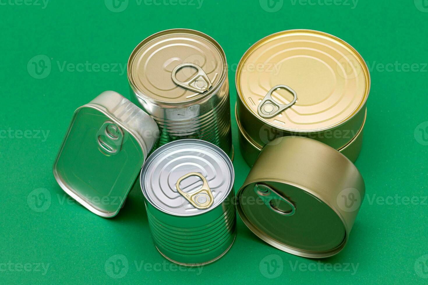 un grupo de apilado estaño latas con blanco bordes en verde antecedentes. Enlatado alimento. diferente aluminio latas para seguro y largo término almacenamiento de alimento. acero sellado comida almacenamiento contenedores foto