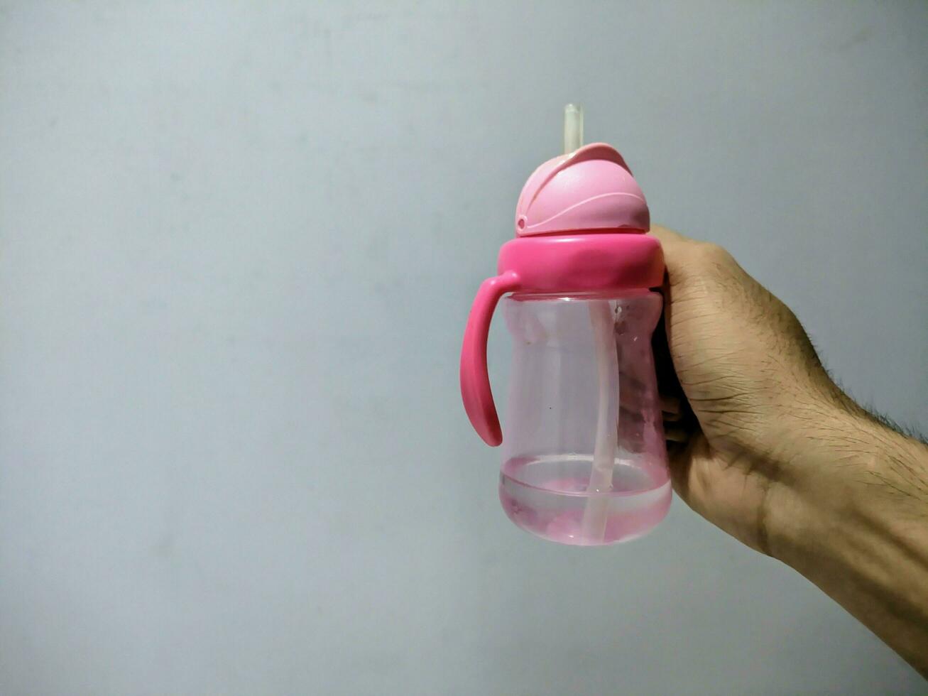 un rosado para niños bebida botella retenida en el Derecha mano foto