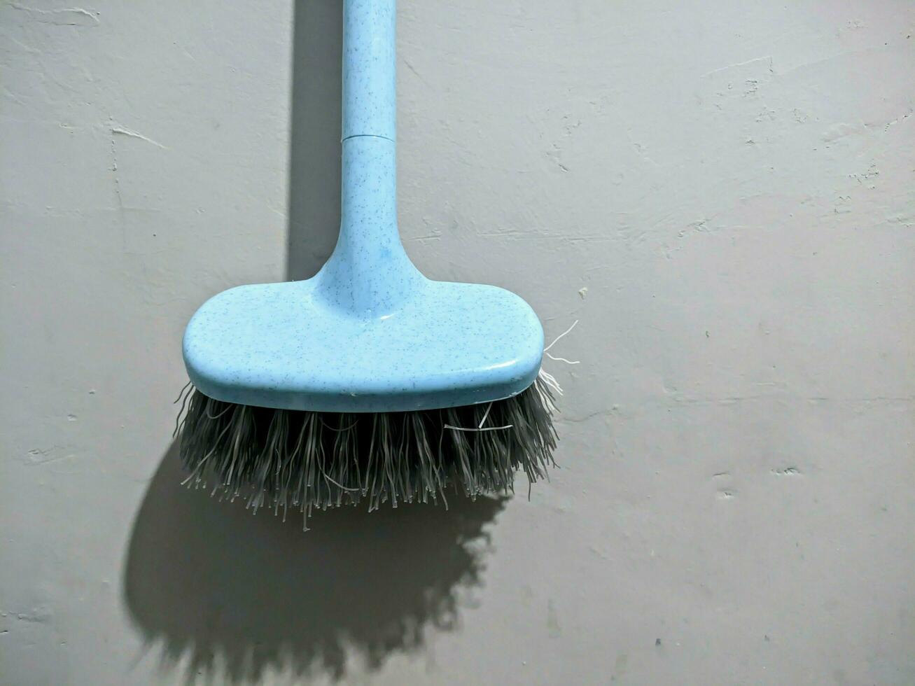 The toilet brush is blue with gray bristles photo