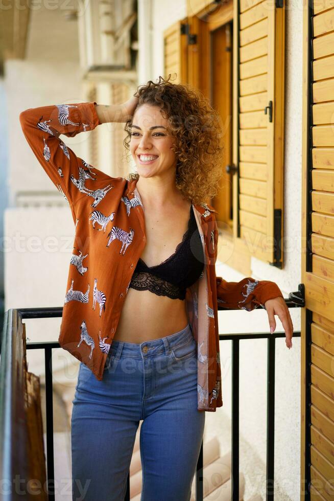 sonriente joven elegante mujer propensión en balcón de moderno casa foto