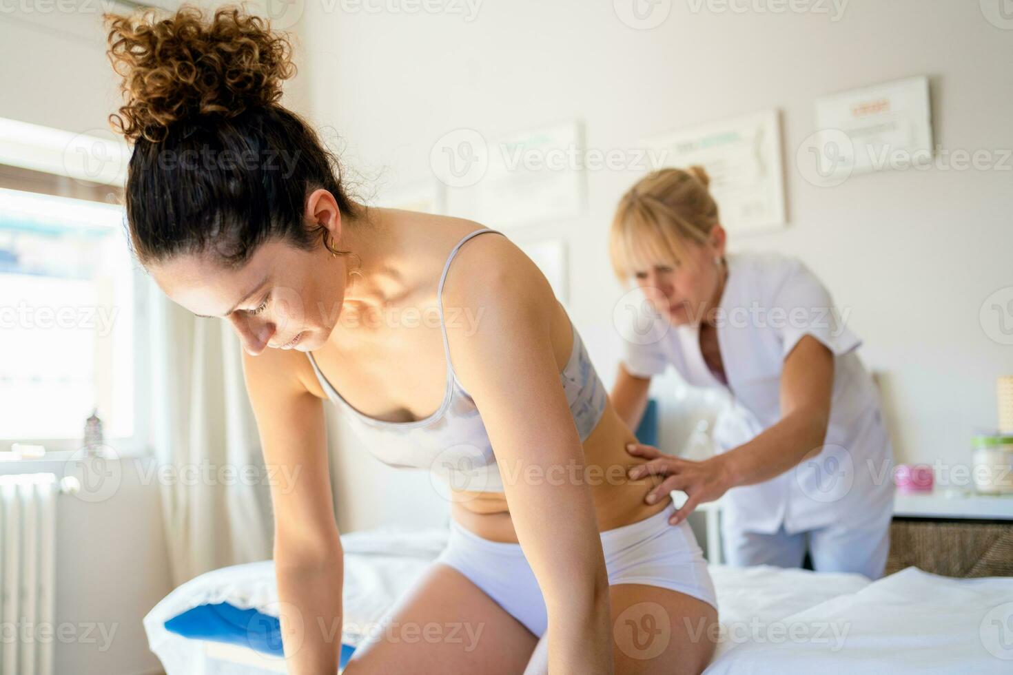 Focused masseuse massaging back of client in clinic photo