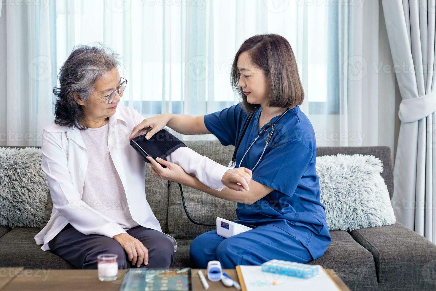 Senior woman got medical service visit from caregiver nurse at home while having blood pressure test using sphygmomanometer on for health care and pension welfare insurance photo