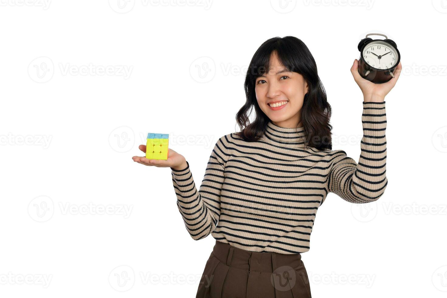 Asian woman holding alarm clock and puzzle cube standing on white background. solving cubic problems, problem solution and making strategic moves concept photo