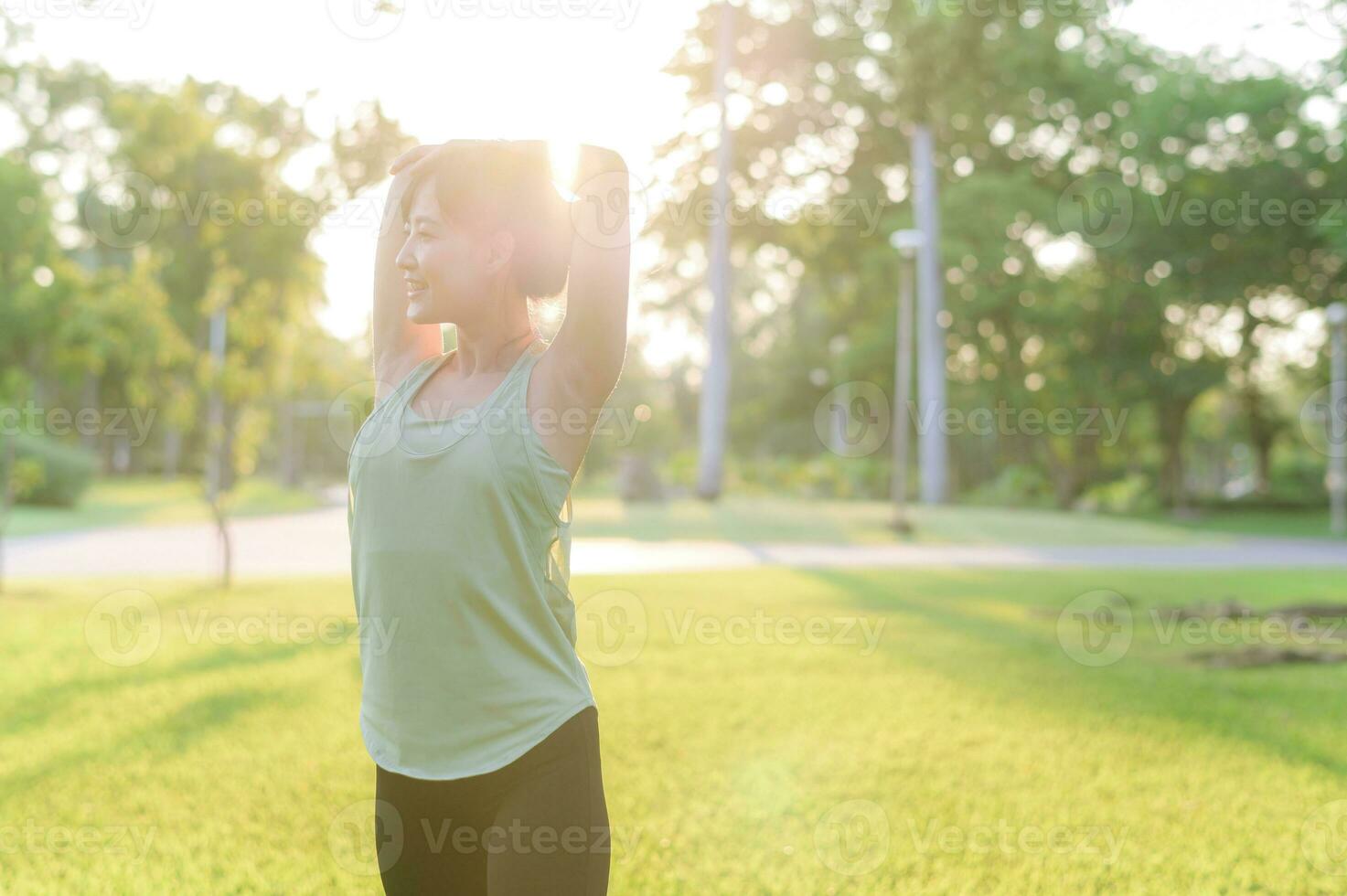 hembra persona que practica jogging. ajuste joven asiático mujer con verde ropa de deporte extensión músculo en parque antes de corriendo y disfrutando un sano exterior. aptitud corredor niña en público parque. bienestar siendo concepto foto