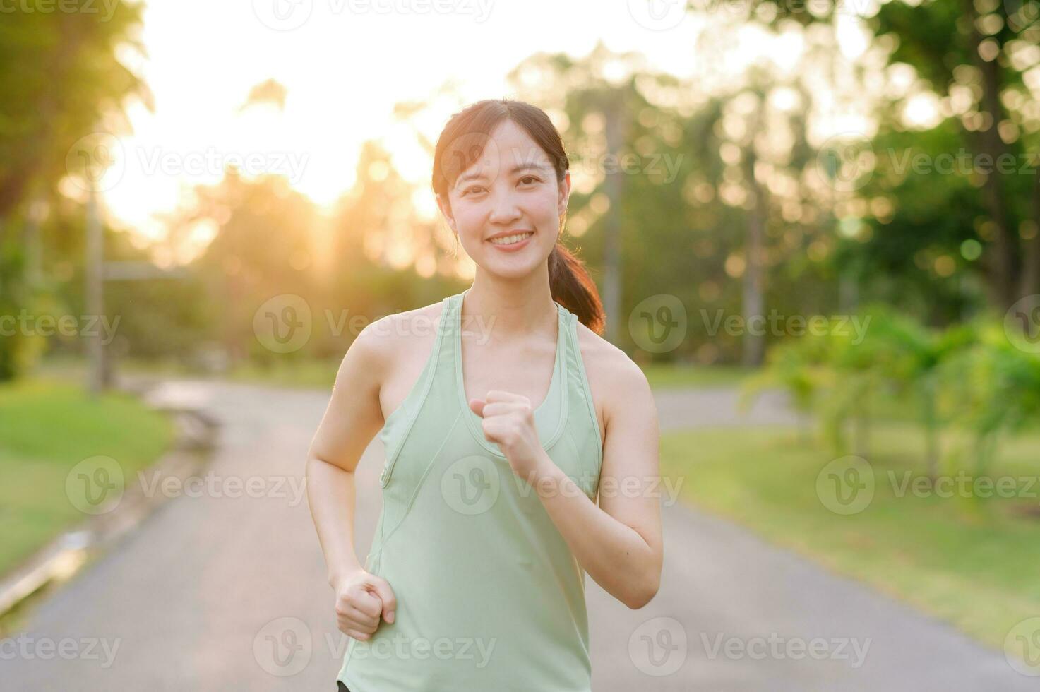 Fit Asian young woman jogging in park smiling happy running and enjoying a healthy outdoor lifestyle. Female jogger. Fitness runner girl in public park. healthy lifestyle and wellness being concept photo