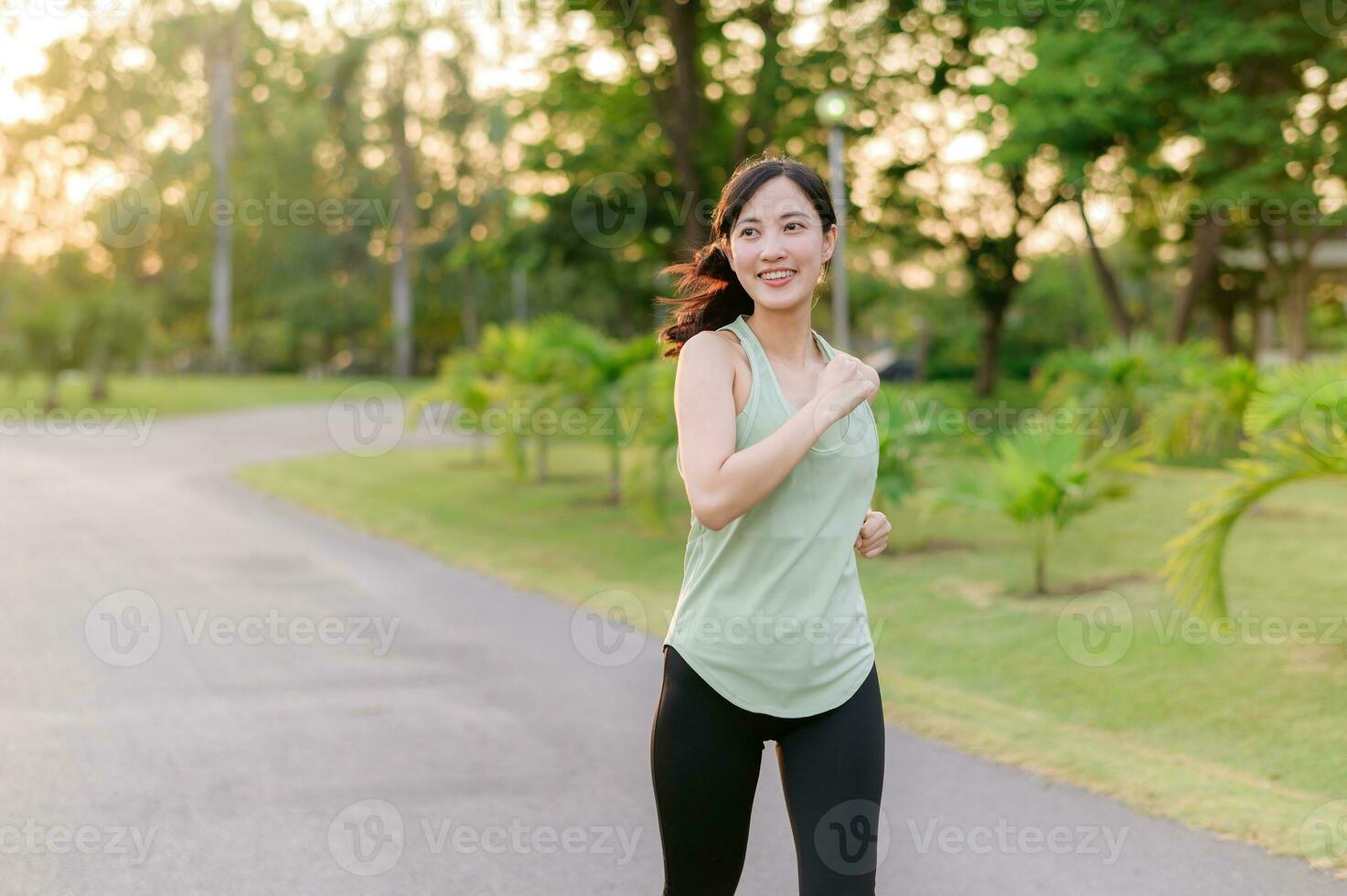 Fit Asian young woman jogging in park smiling happy running and enjoying a healthy outdoor lifestyle. Female jogger. Fitness runner girl in public park. healthy lifestyle and wellness being concept photo