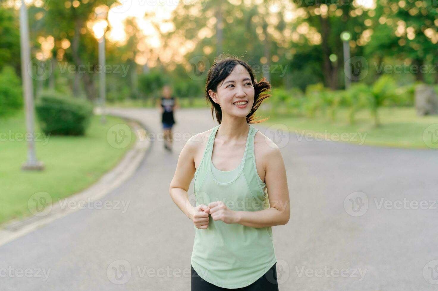 Fit Asian young woman jogging in park smiling happy running and enjoying a healthy outdoor lifestyle. Female jogger. Fitness runner girl in public park. healthy lifestyle and wellness being concept photo