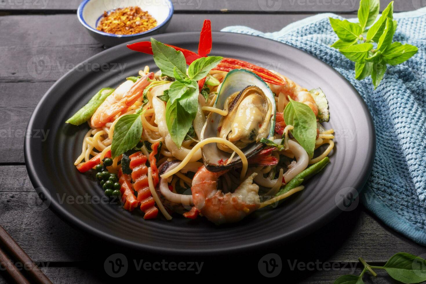 Seafood drunken spaghetti with shrimp squid clams chili, and basil. Thai food. Healthy Asian in a plate on a black background table. Top view. photo