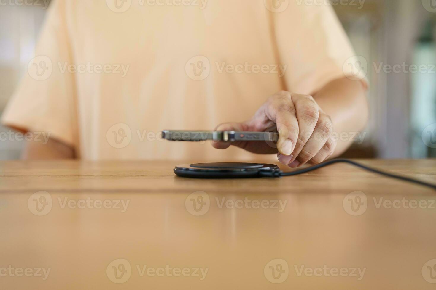 Charging mobile phone battery with wireless charging device in the table. Smartphone charging on a charging pad. Mobile phone near wireless charger Modern lifestyle technology concept. photo