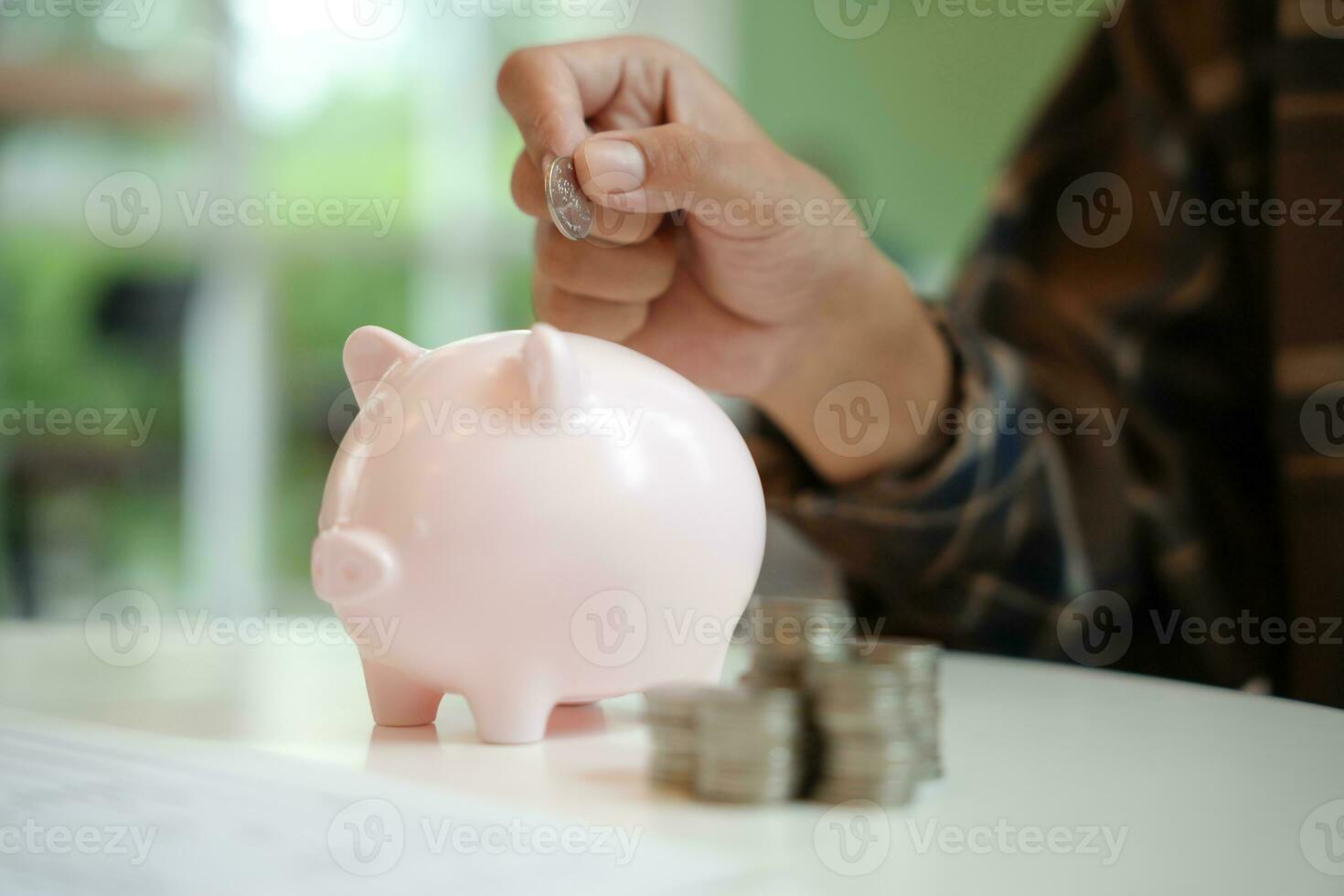 Saving money. hand putting money into pink piggy bank making investments or strategy for personal savings photo