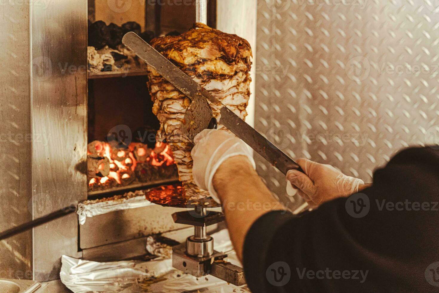 Chef slicing meat from skewer for cooking shawarma - Popular fast food delicacy photo