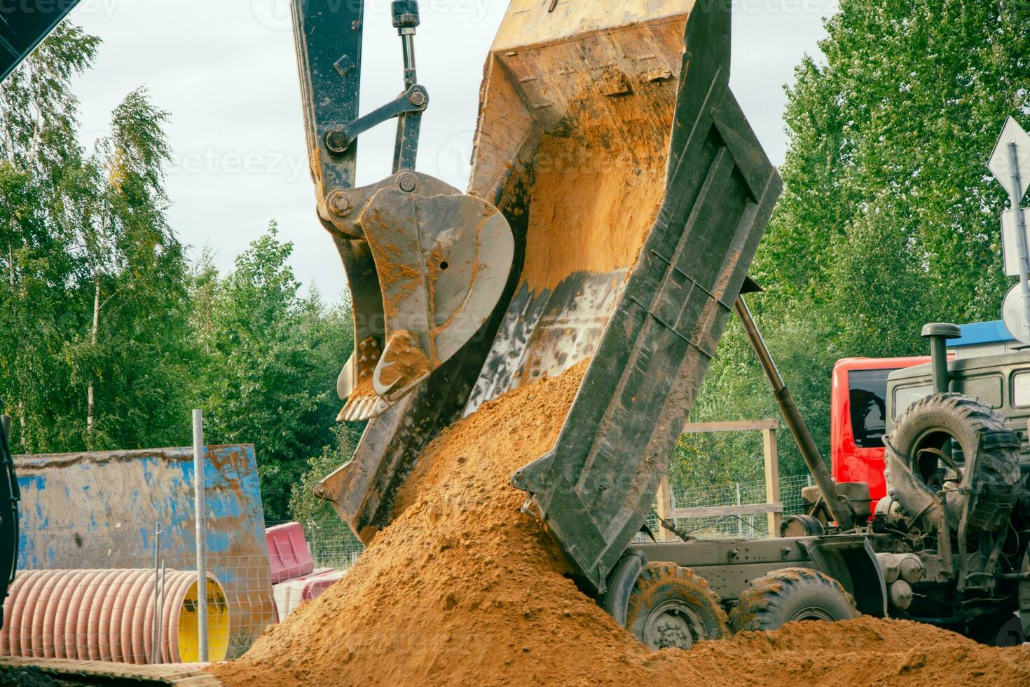 excavador Cubeta descarga arena desde camión cuerpo a construcción sitio foto