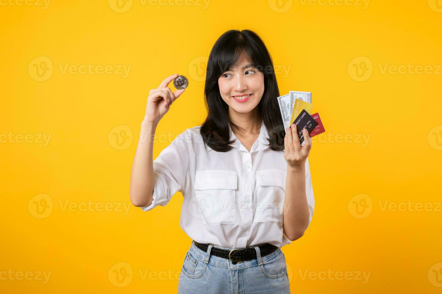 Capture the essence of digital currency with stunning portrait of young Asian woman confidently holds digital currency, cash, credit card, and smartphone. The digital currency concept. photo
