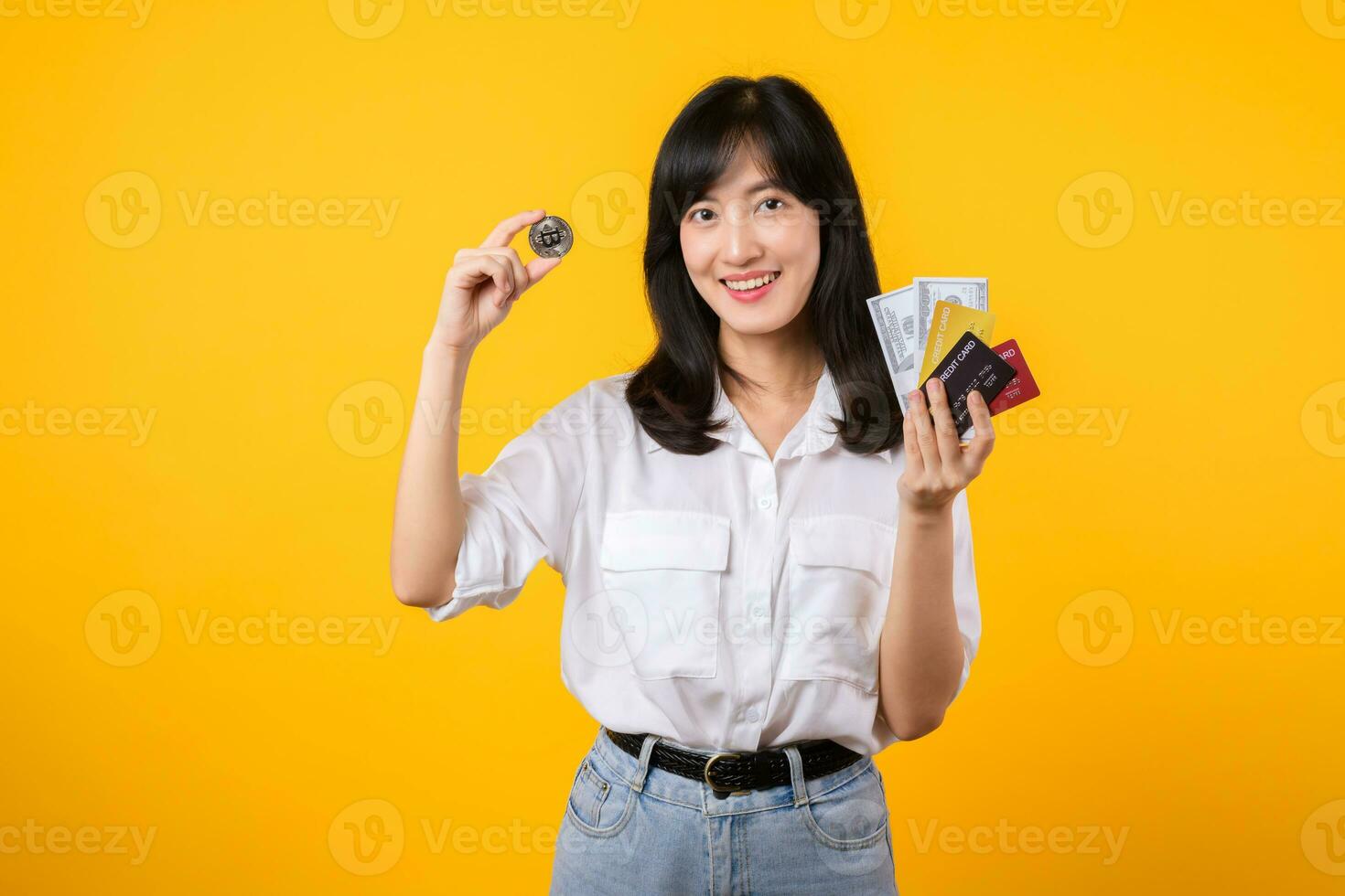 Capture the essence of digital currency with stunning portrait of young Asian woman confidently holds digital currency, cash, credit card, and smartphone. The digital currency concept. photo