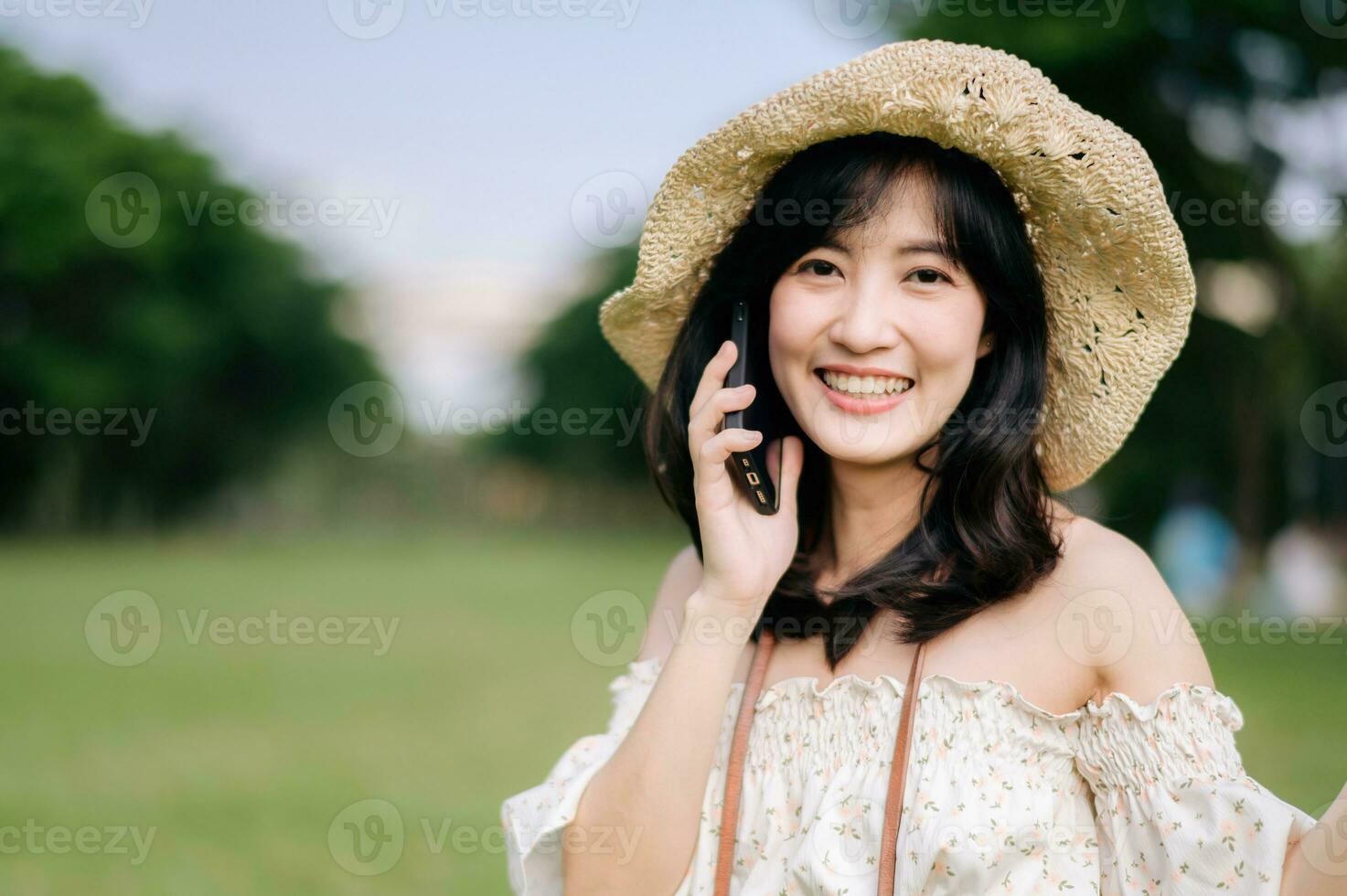 Portrait of asian young woman traveler with weaving hat, basket, mobile phone and camera on green public park background. Journey trip lifestyle, world travel explorer or Asia summer tourism concept. photo