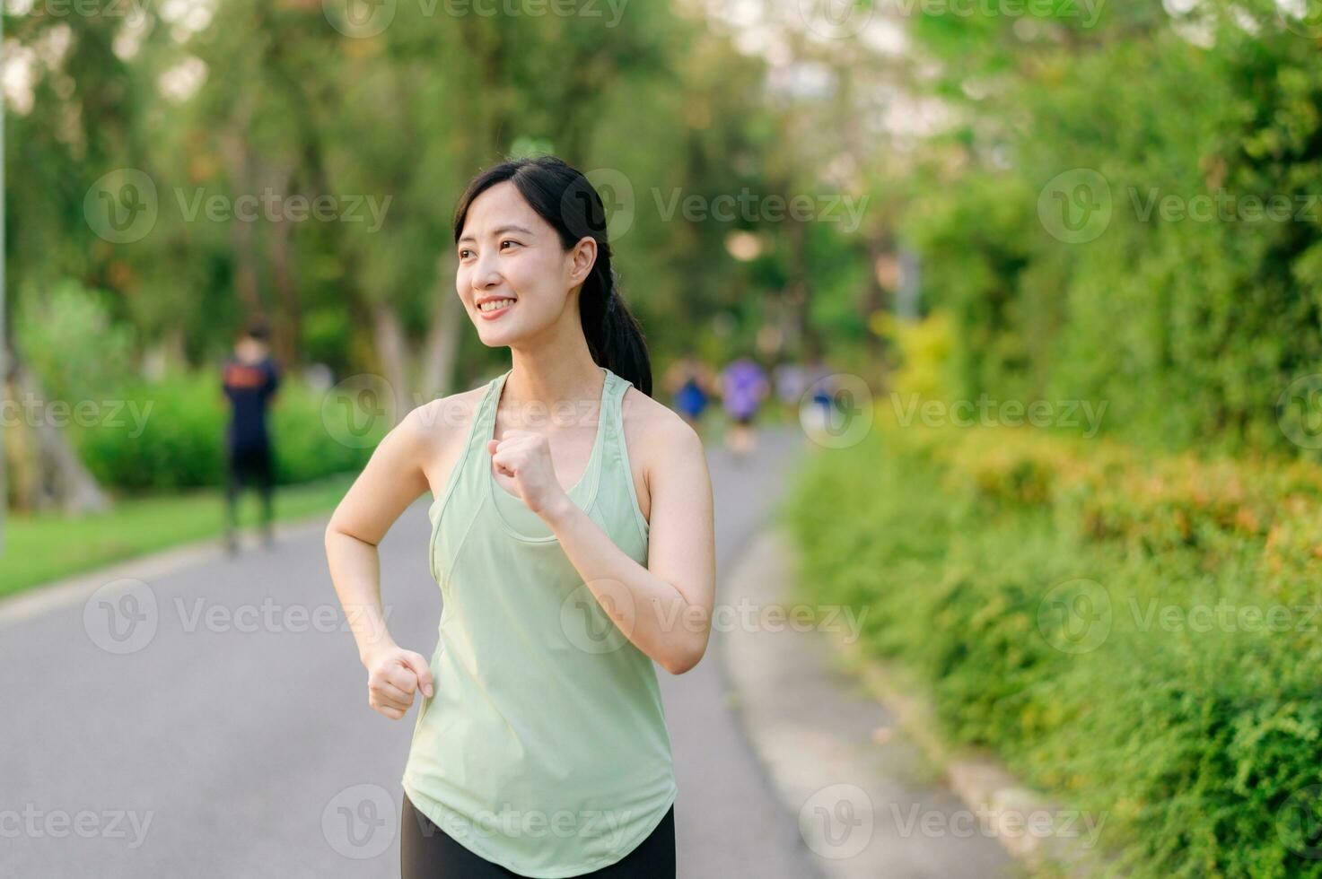 Fit Asian young woman jogging in park smiling happy running and enjoying a healthy outdoor lifestyle. Female jogger. Fitness runner girl in public park. healthy lifestyle and wellness being concept photo