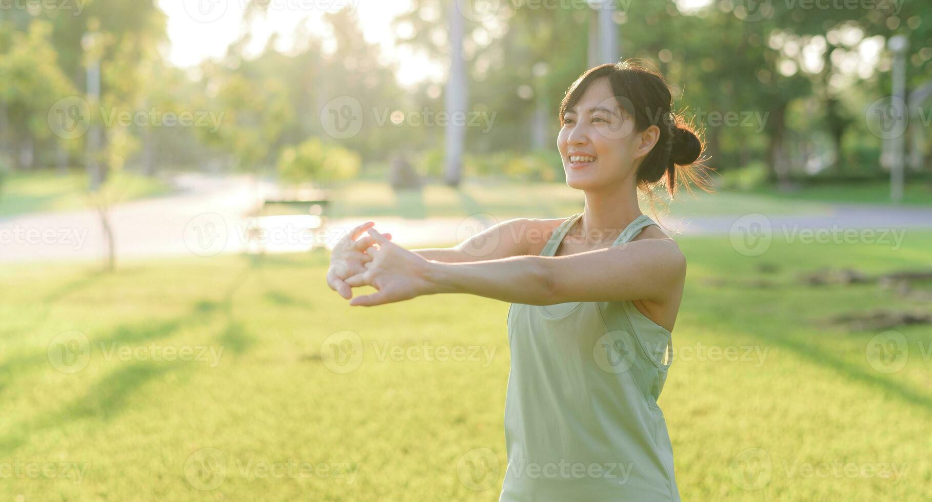 Female jogger. Fit young Asian woman with green sportswear stretching muscle in park before running and enjoying a healthy outdoor. Fitness runner girl in public park. Wellness being concept photo