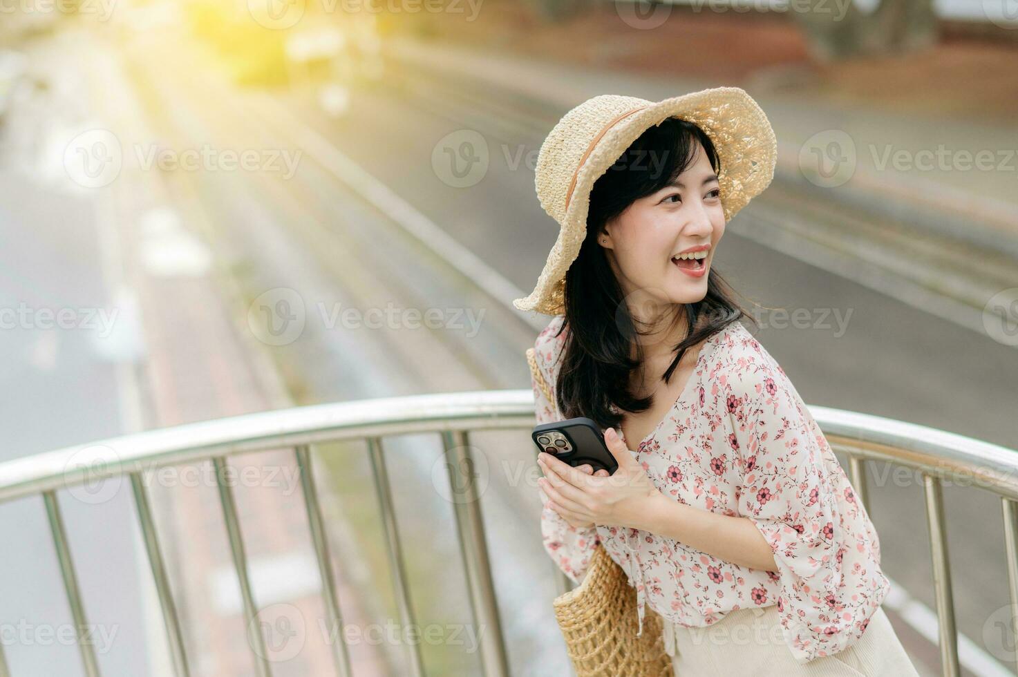 young asian woman traveler with weaving basket using mobile phone and standing on overpass with railway background. Journey trip lifestyle, world travel explorer or Asia summer tourism concept. photo
