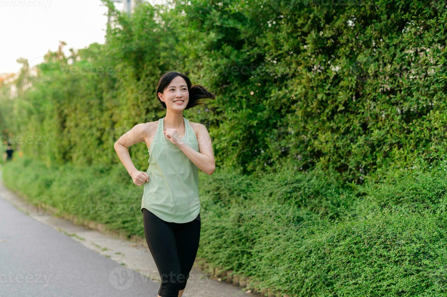 Fit Asian young woman jogging in park smiling happy running and enjoying a healthy outdoor lifestyle. Female jogger. Fitness runner girl in public park. healthy lifestyle and wellness being concept photo