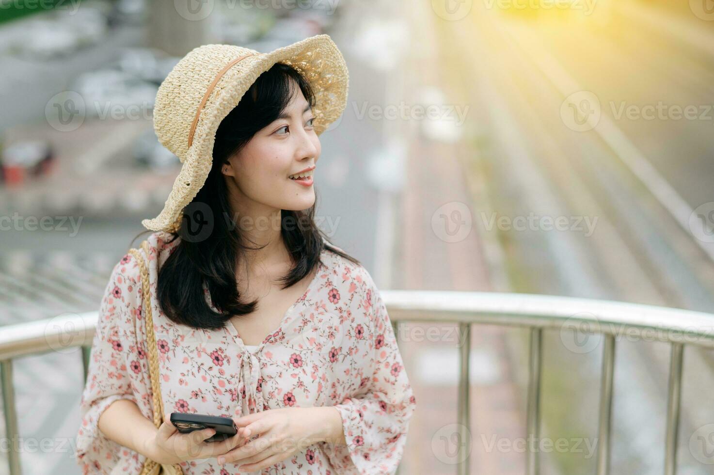 young asian woman traveler with weaving basket using mobile phone and standing on overpass with railway background. Journey trip lifestyle, world travel explorer or Asia summer tourism concept. photo