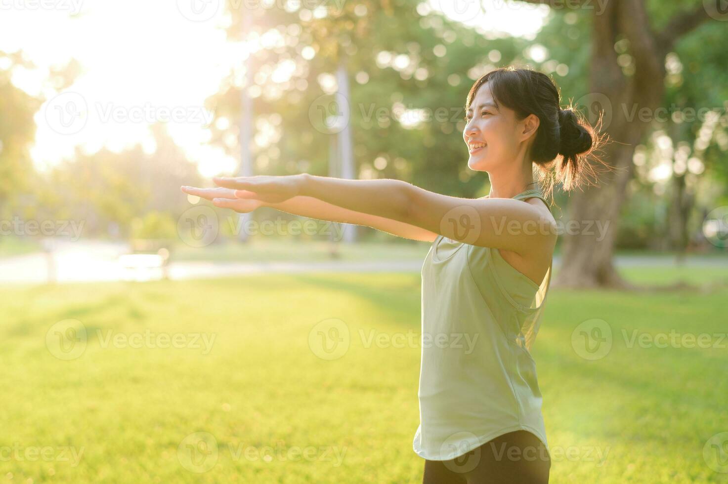 Female jogger. Fit young Asian woman with green sportswear stretching muscle in park before running and enjoying a healthy outdoor. Fitness runner girl in public park. Wellness being concept photo