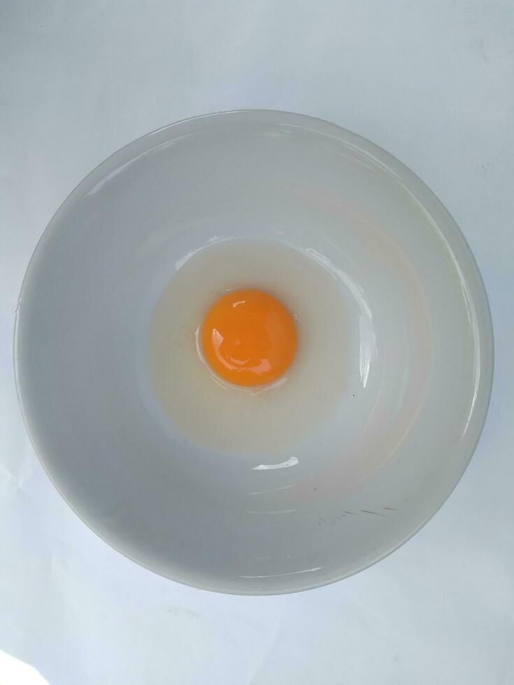 Raw eggs, top view of one raw eggs yolk in bowl on isolated white background. photo