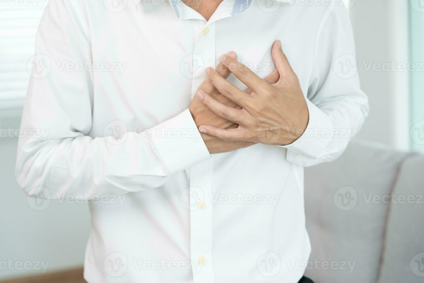 hand hold chest with heart attack symptoms, asian man working hard have chest pain caused by heart disease, leak, dilatation, enlarged coronary heart, press on the chest with a painful expression photo